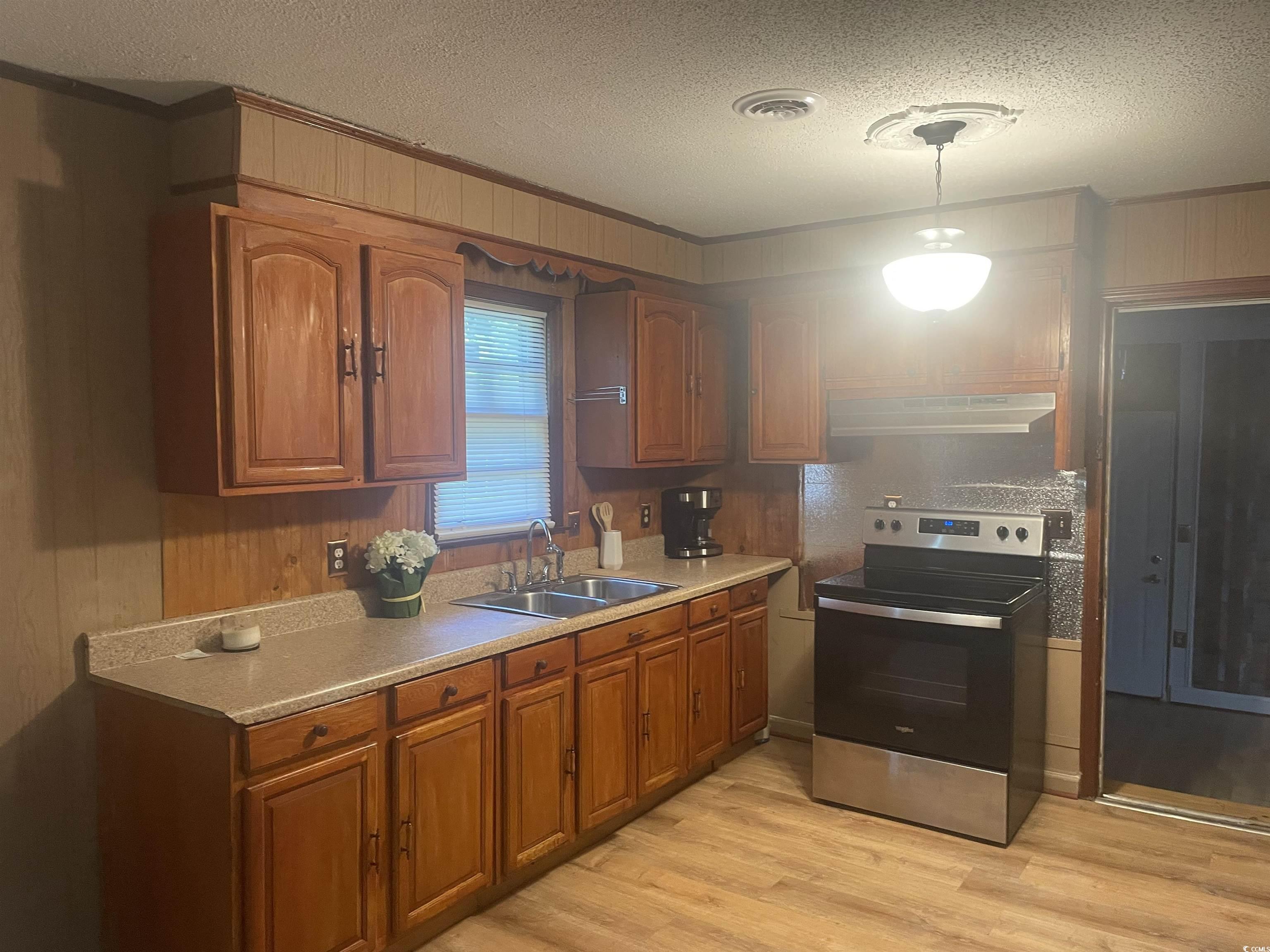 704 West Alder Street Andrews, SC 29510 - Photo 4 of 12 Kitchen with electric range, brown cabinetry, decorative light fixtures, a textured ceiling, and light countertops