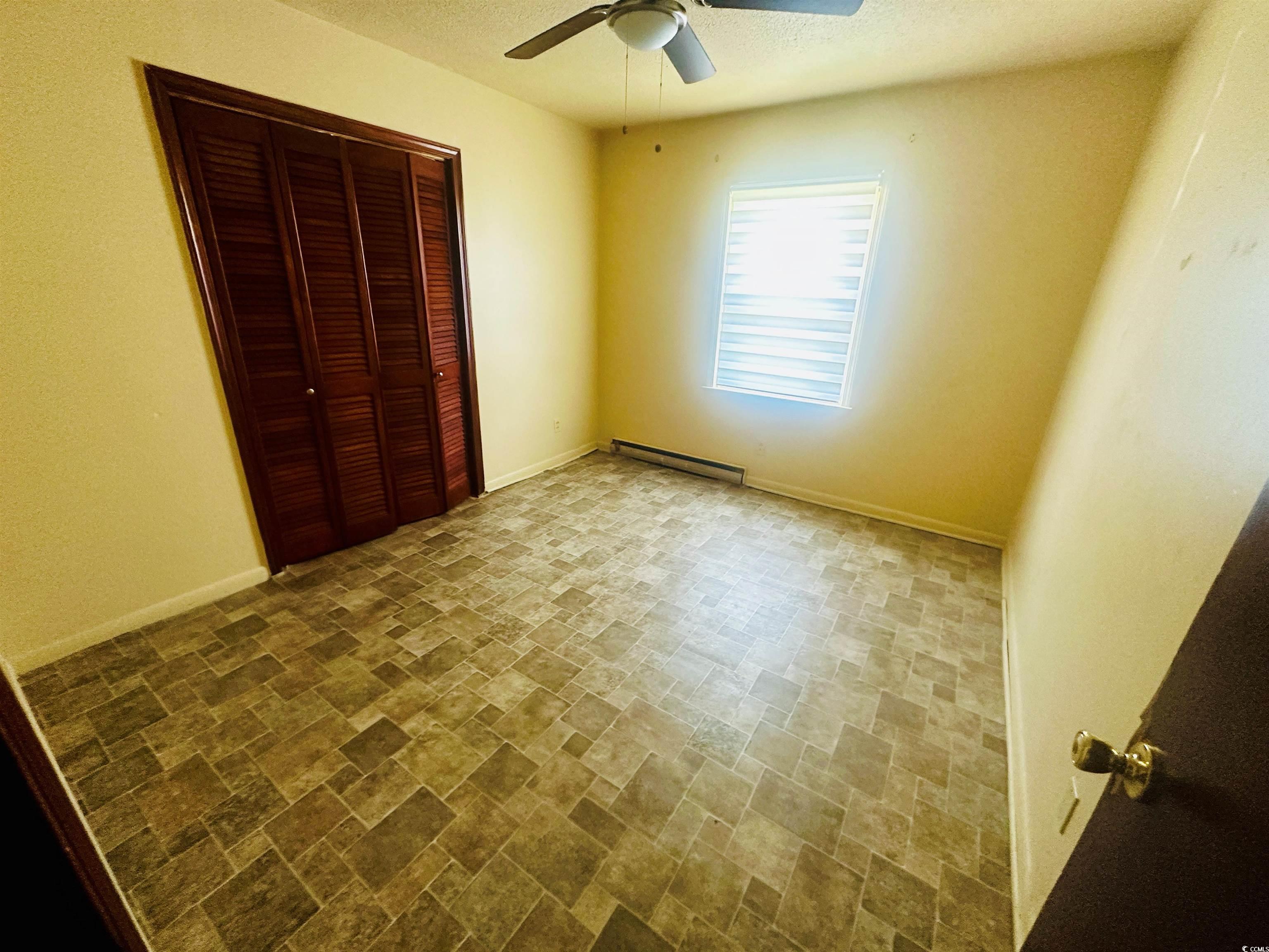 704 West Alder Street Andrews, SC 29510 - Photo 6 of 12 Unfurnished bedroom featuring a textured ceiling, a closet, a baseboard radiator, and ceiling fan