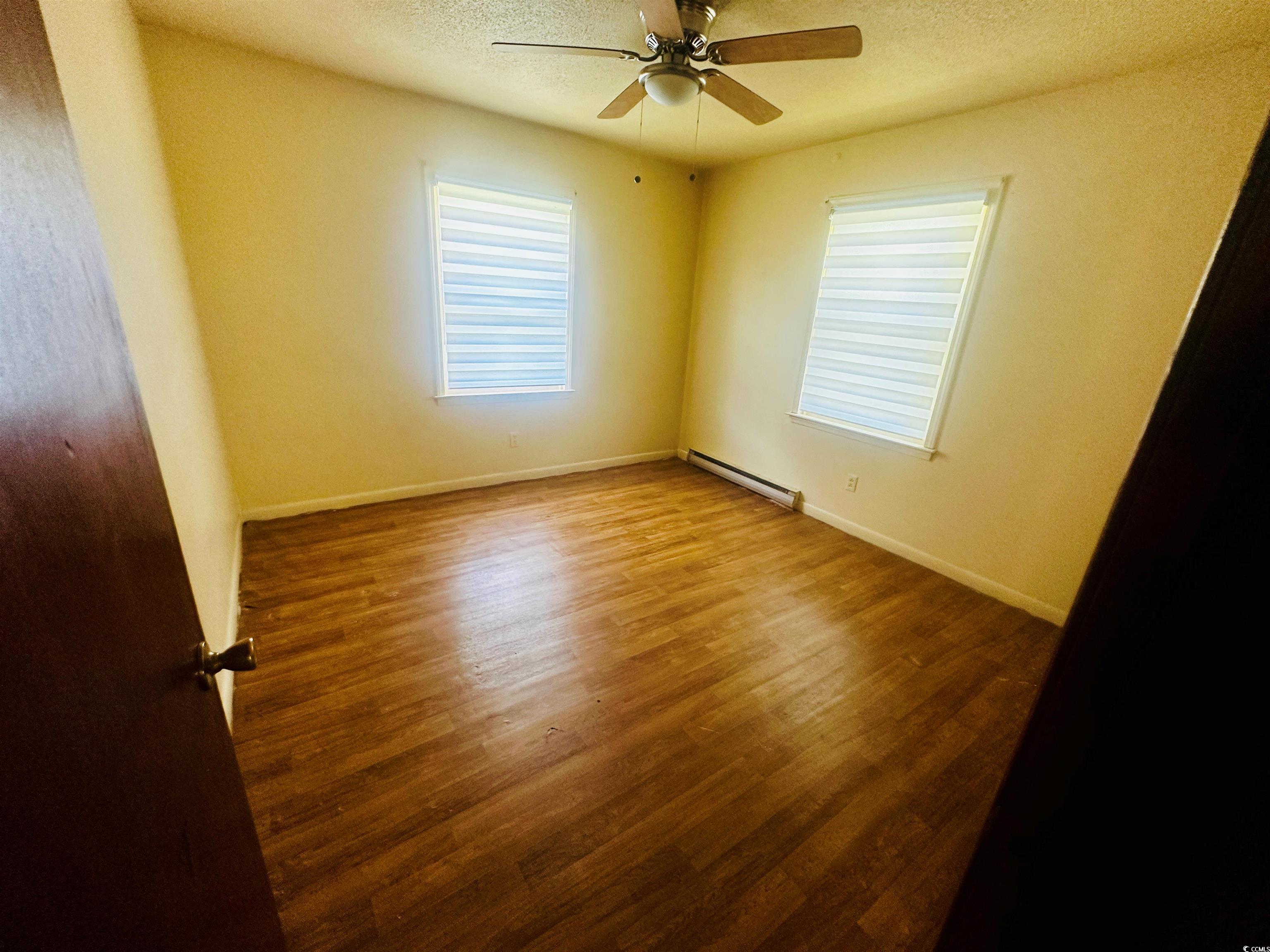 704 West Alder Street Andrews, SC 29510 - Photo 7 of 12 Spare room featuring a textured ceiling, wood finished floors, a baseboard radiator, and a ceiling fan