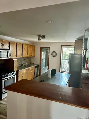 a kitchen with stainless steel appliances granite countertop a refrigerator a stove and a sink with wooden floor