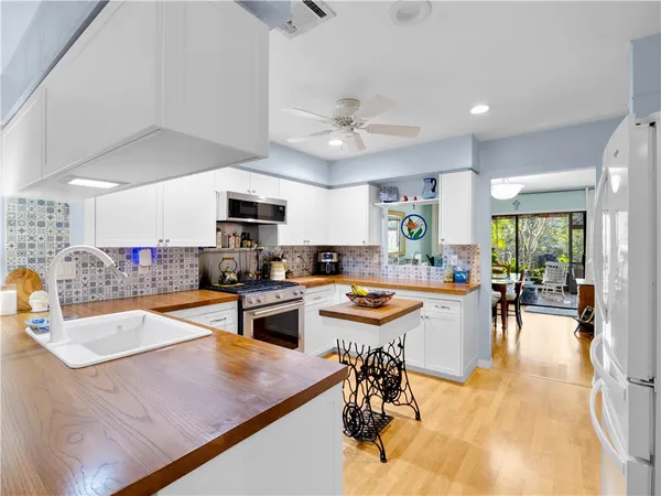 a dining hall with stainless steel appliances granite countertop a sink a stove and chairs with wooden floor