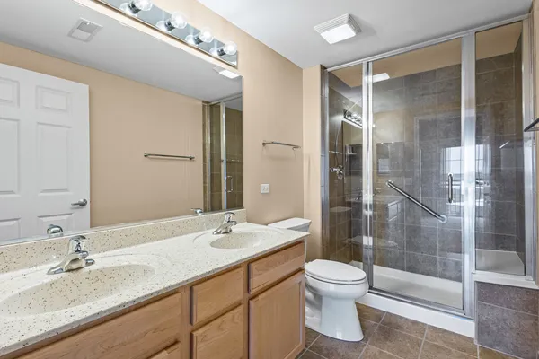 a bathroom with a granite countertop sink toilet a mirror and shower