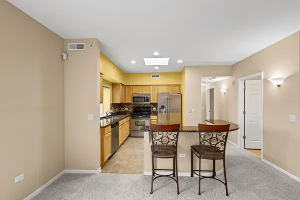 a kitchen with stainless steel appliances kitchen island granite countertop a refrigerator a stove a microwave oven with a dining table and chairs