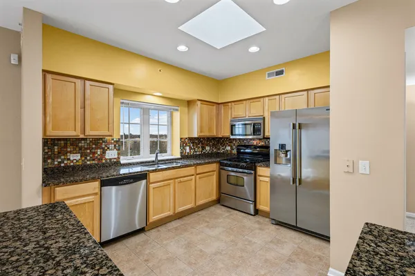 a kitchen with stainless steel appliances granite countertop a refrigerator and a sink
