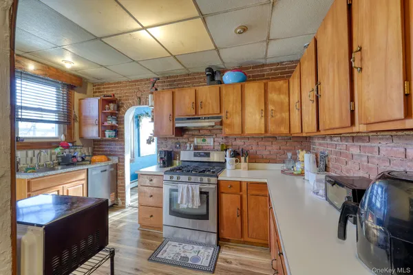 a kitchen with stainless steel appliances granite countertop a stove a refrigerator a sink dishwasher a dining table and chairs with wooden floor