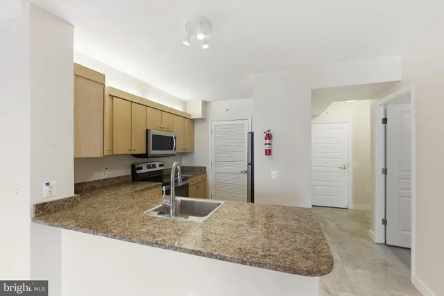 a kitchen with sink refrigerator and faucet
