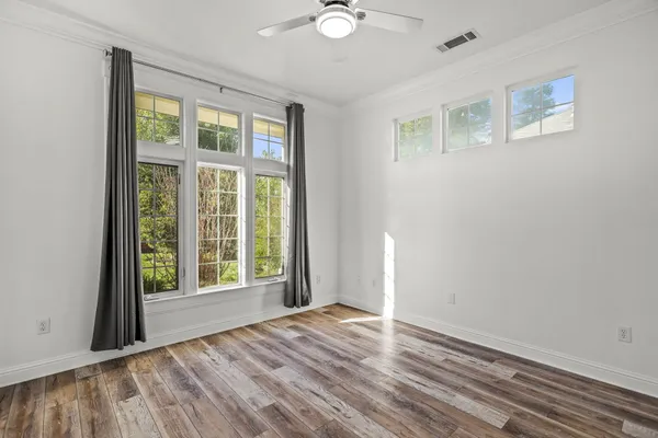 an empty room with wooden floor and windows