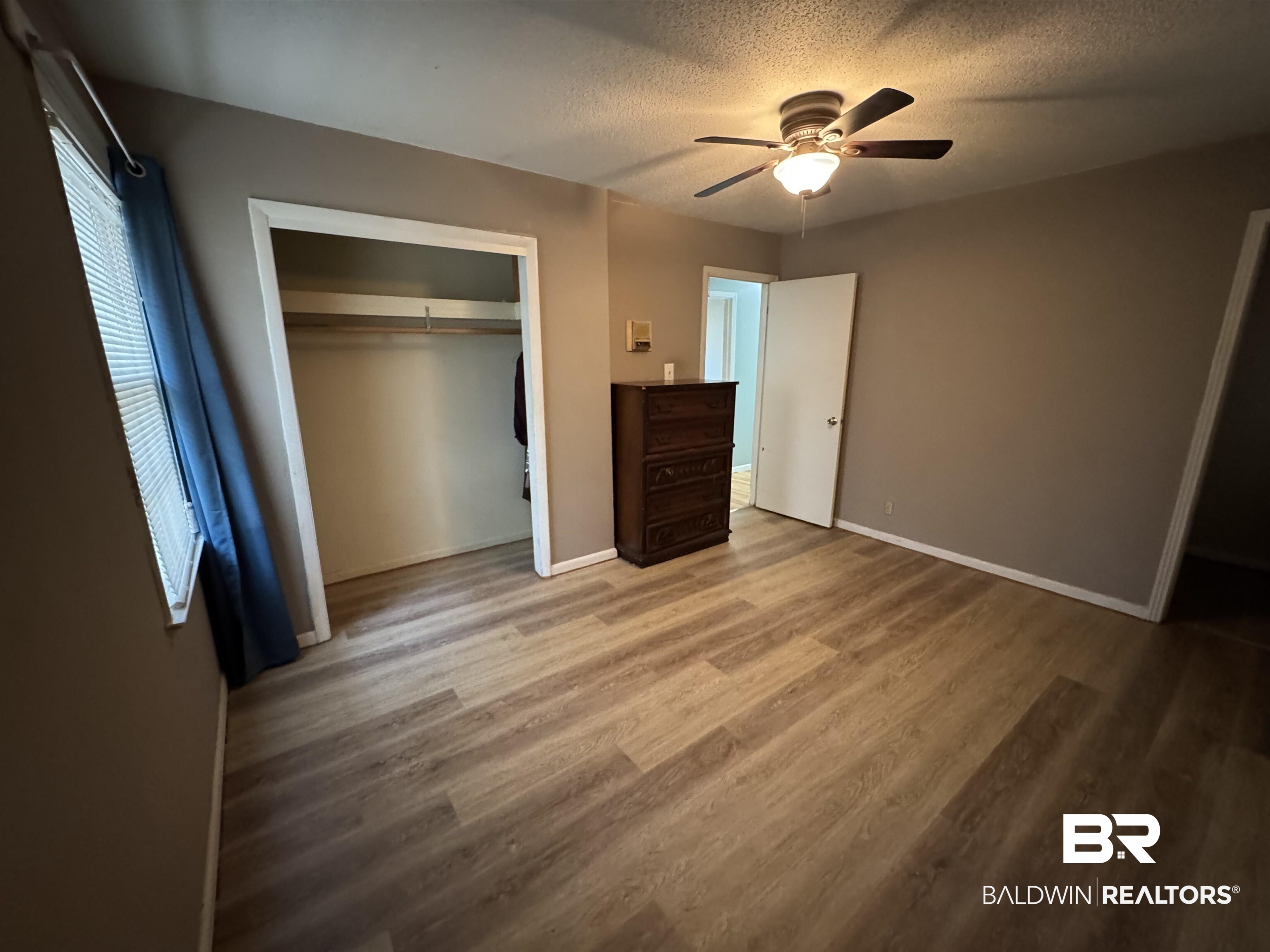 8065 Middle Ring Road Mobile, AL 36619 - Photo 20 of 21 Unfurnished bedroom featuring a closet, baseboards, a textured ceiling, and wood finished floors