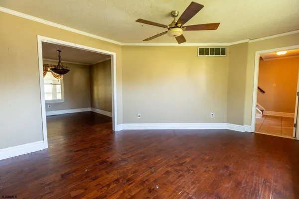 an empty room with wooden floor and a ceiling fan