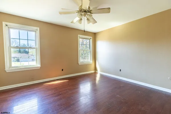 an empty room with windows and chandelier fan