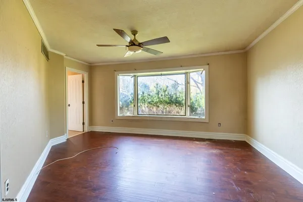an empty room with wooden floor fan and windows