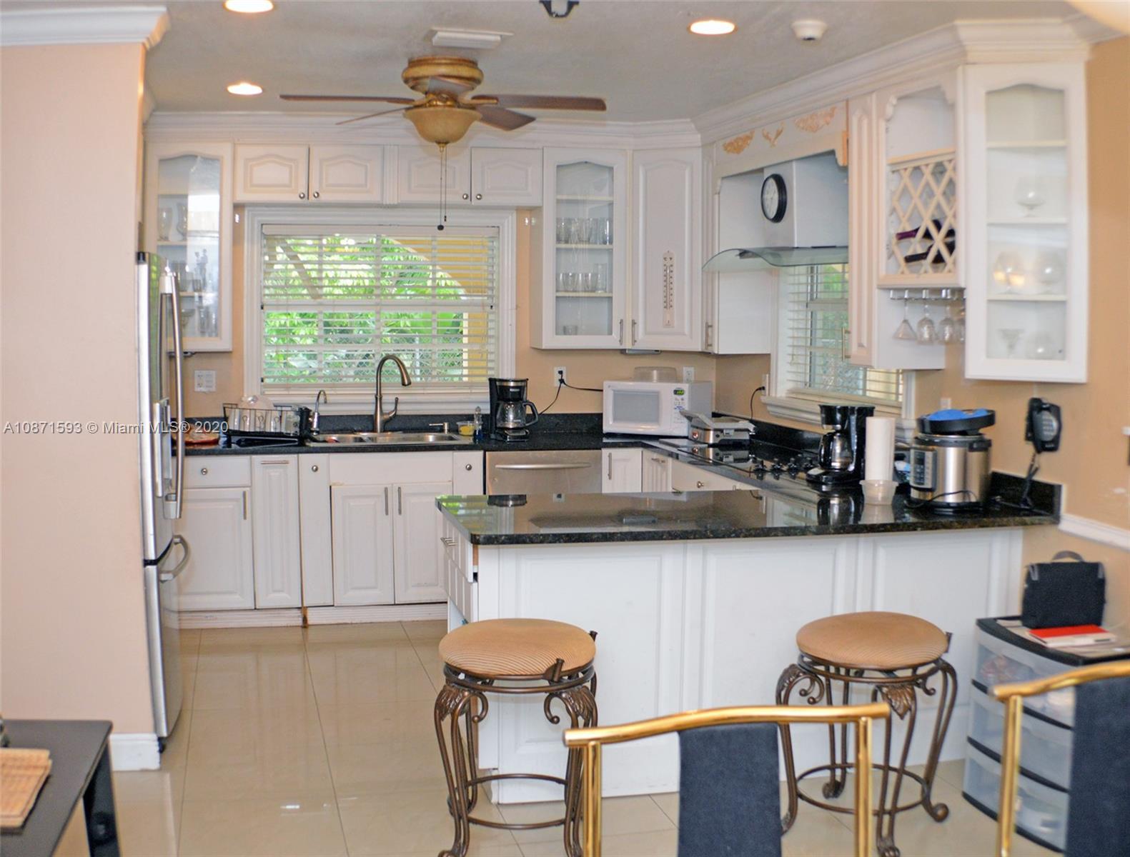 6500 Southwest 148th Avenue Southwest Ranches, FL 33330 - Photo 3 of 25 a kitchen with stainless steel appliances granite countertop a table chairs in it and white cabinets