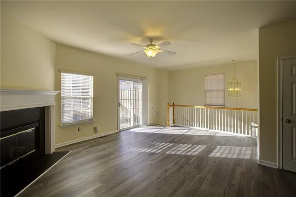 an empty room with wooden floor fireplace and windows