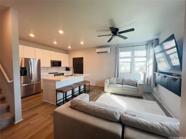 a living room with stainless steel appliances furniture and a kitchen view