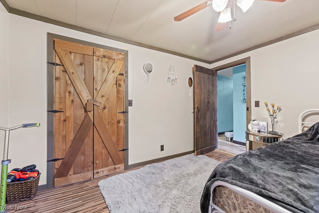 3271 Gorge Road Southwest Dellroy, OH 44620 - Photo 28 of 48 Bedroom featuring a barn door, hardwood / wood-style flooring, and ceiling fan