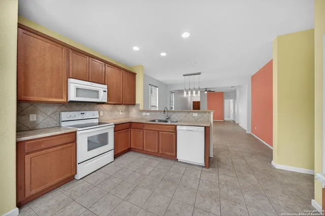 a kitchen with stainless steel appliances granite countertop a stove top oven a sink and dishwasher a refrigerator with wooden cabinets