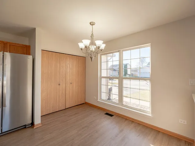an empty room with wooden floor cabinet and windows