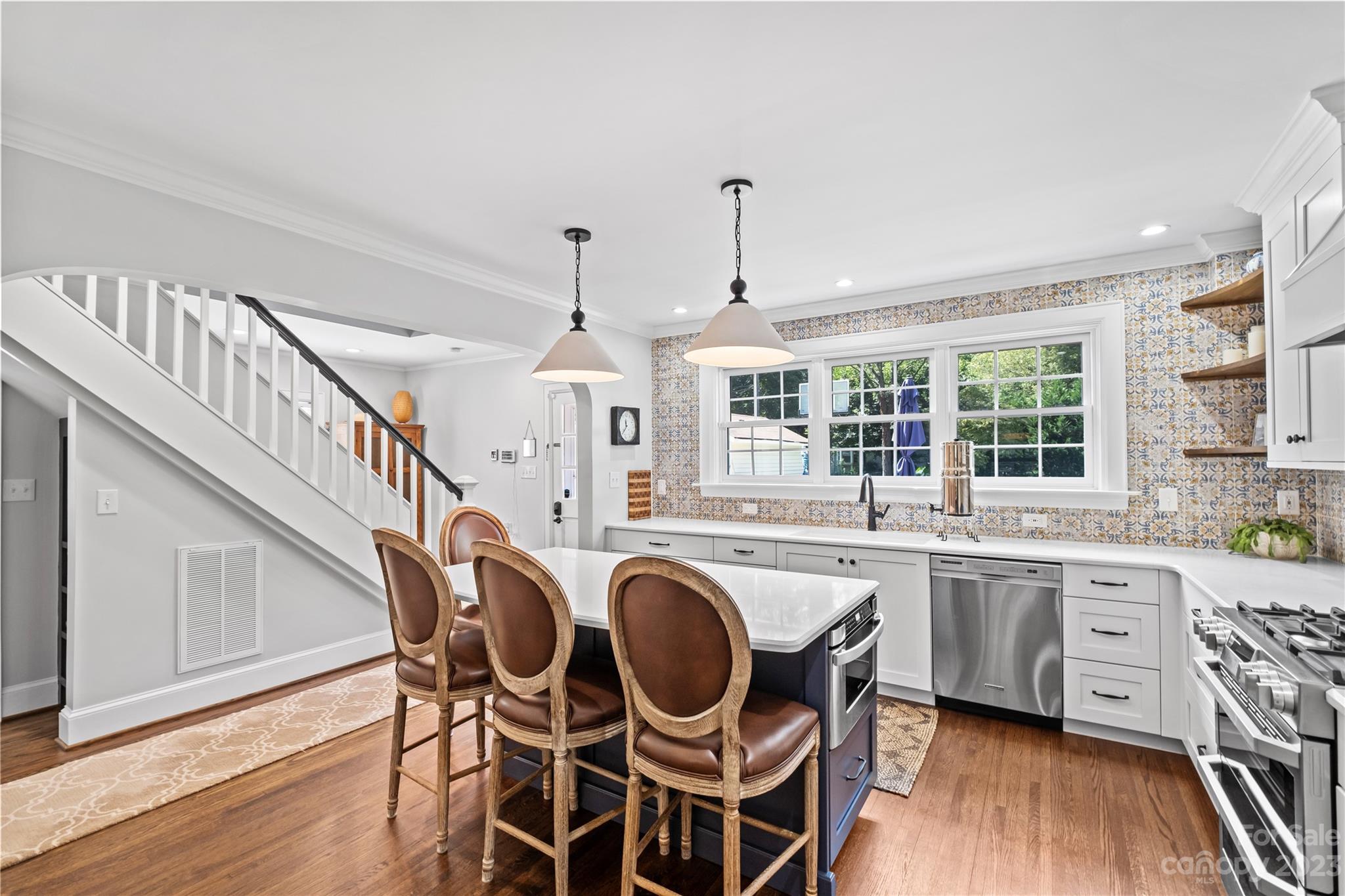 1324 Goodwin Avenue Charlotte, NC 28205 - Photo 7 of 29 a open kitchen with stainless steel appliances kitchen island granite countertop a stove a sink a dining table and chairs with wooden floor