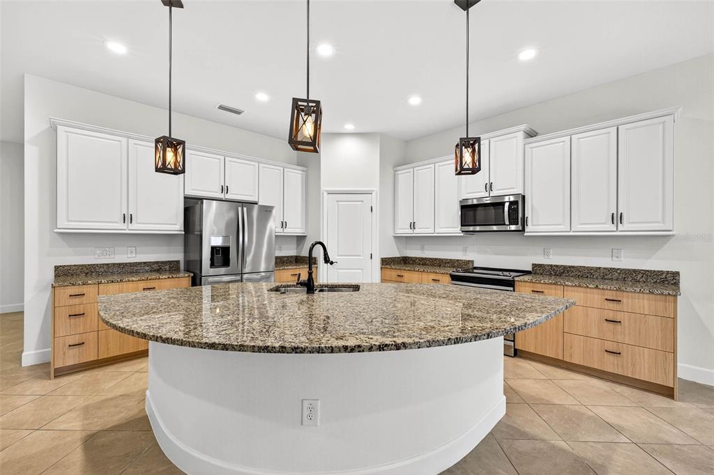 33487 Azalea Ridge Drive Wesley Chapel, FL 33545 - Photo 11 of 56 a kitchen with stainless steel appliances granite countertop a sink a stove and oven a refrigerator with wooden floor