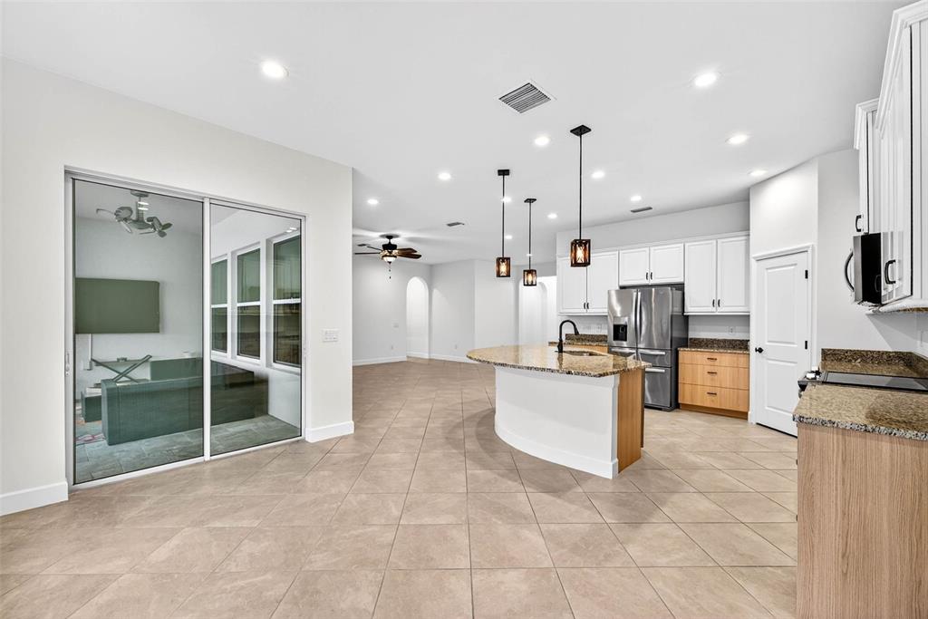 33487 Azalea Ridge Drive Wesley Chapel, FL 33545 - Photo 15 of 56 a large kitchen with stainless steel appliances kitchen island granite countertop a refrigerator and a sink