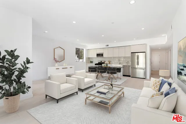 a living room with furniture potted plant and kitchen view
