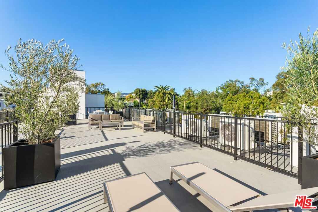11620 Chenault Street, Unit 304 Los Angeles, CA 90049 - Photo 17 of 19 a view of a patio with couches and table and chairs with wooden floor and fence