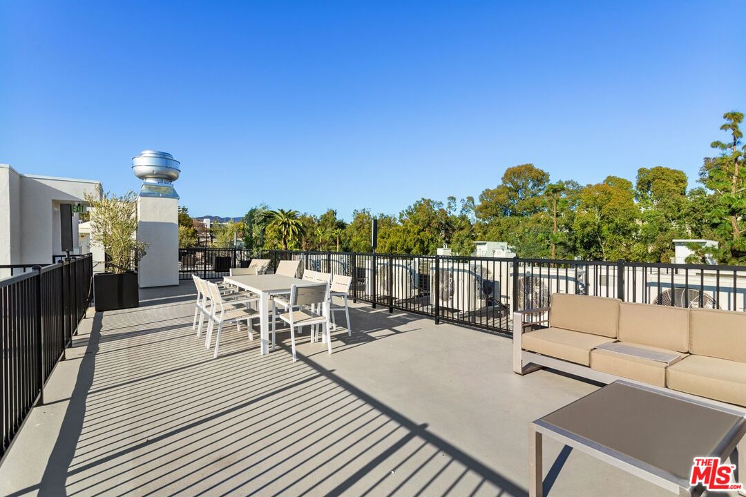 11620 Chenault Street, Unit 304 Los Angeles, CA 90049 - Photo 18 of 19 a view of a patio with a dining table and chairs with wooden floor