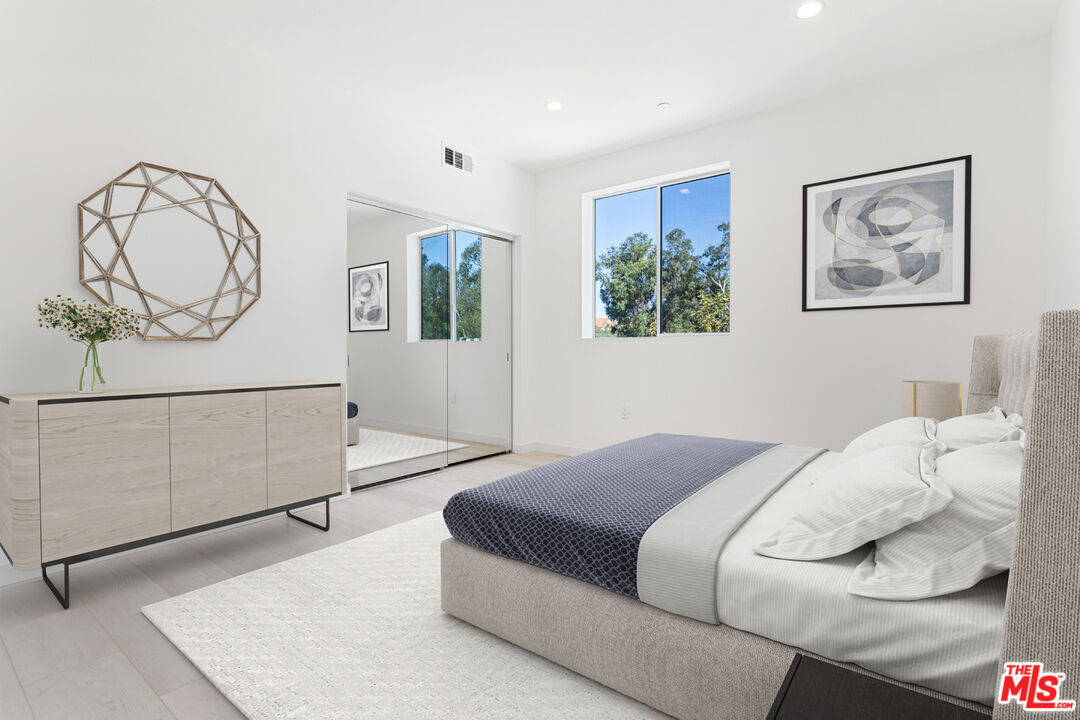 11620 Chenault Street, Unit 304 Los Angeles, CA 90049 - Photo 5 of 19 a bedroom with a bed a mirror and paintings on the wall