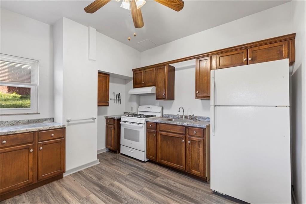 405 Walter Street Pittsburgh, PA 15210 - Photo 11 of 40 a kitchen with stainless steel appliances granite countertop a refrigerator a sink dishwasher a stove top oven a dining table and chairs with wooden floor