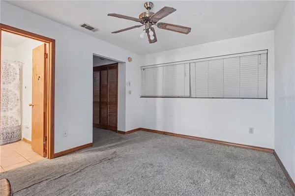 an empty room with windows and fan