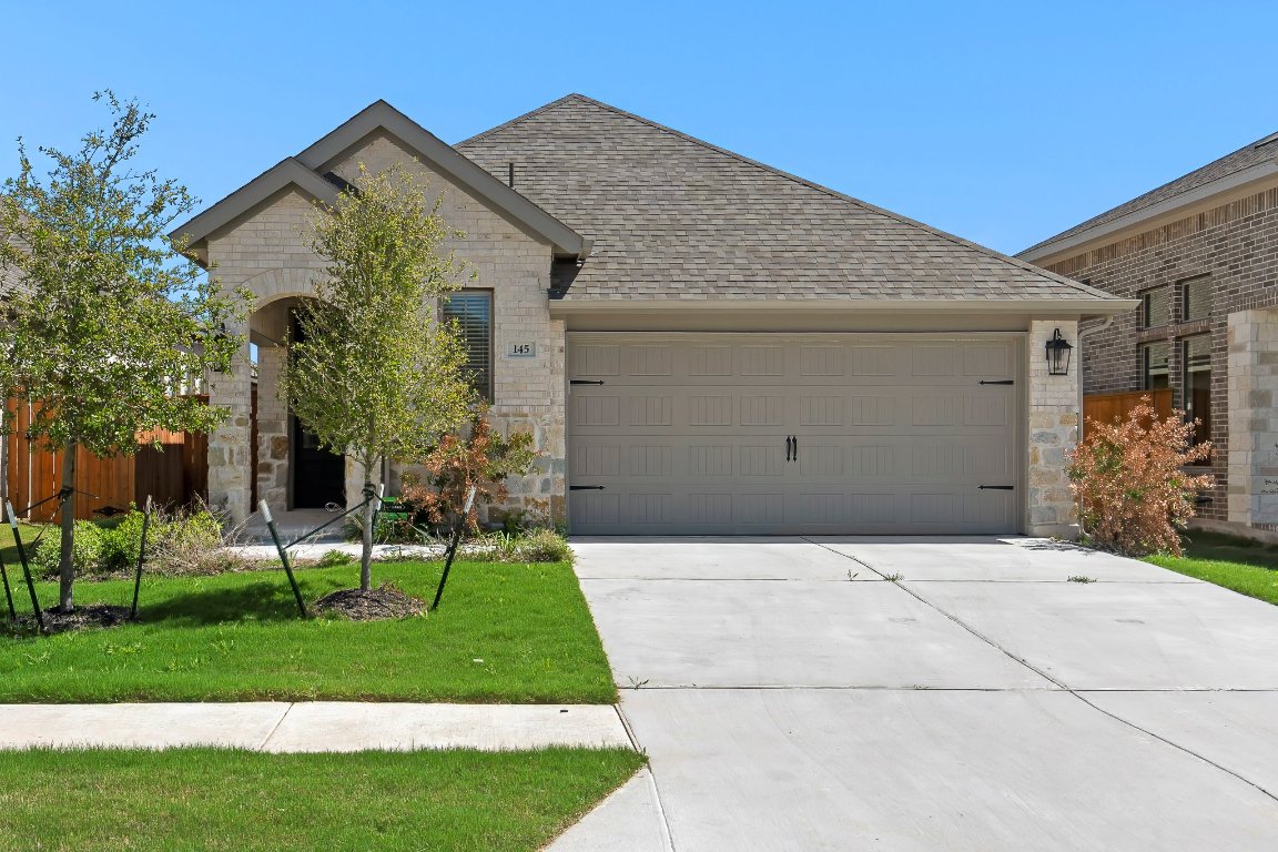 a front view of a house with a garden and trees