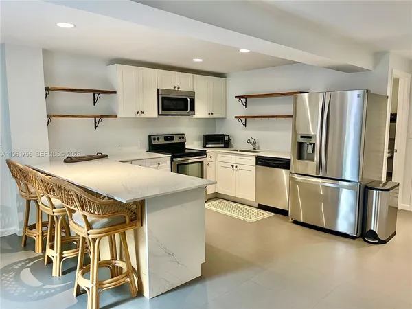 a kitchen with granite countertop white cabinets and stainless steel appliances
