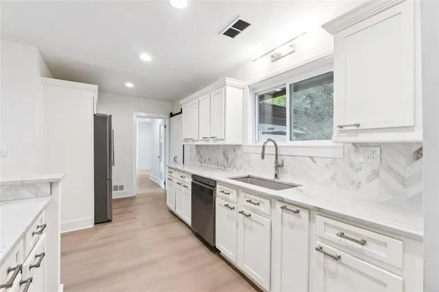 a kitchen with white cabinets and sink