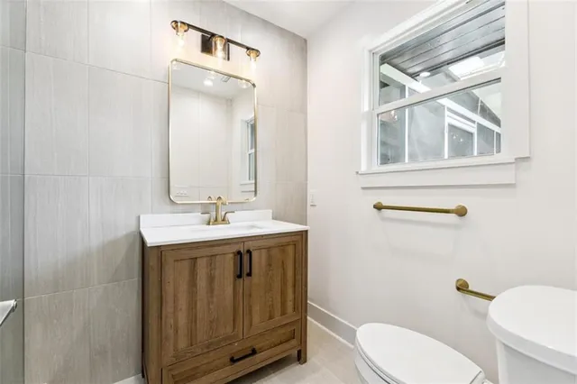 a bathroom with a granite countertop toilet a sink and a mirror