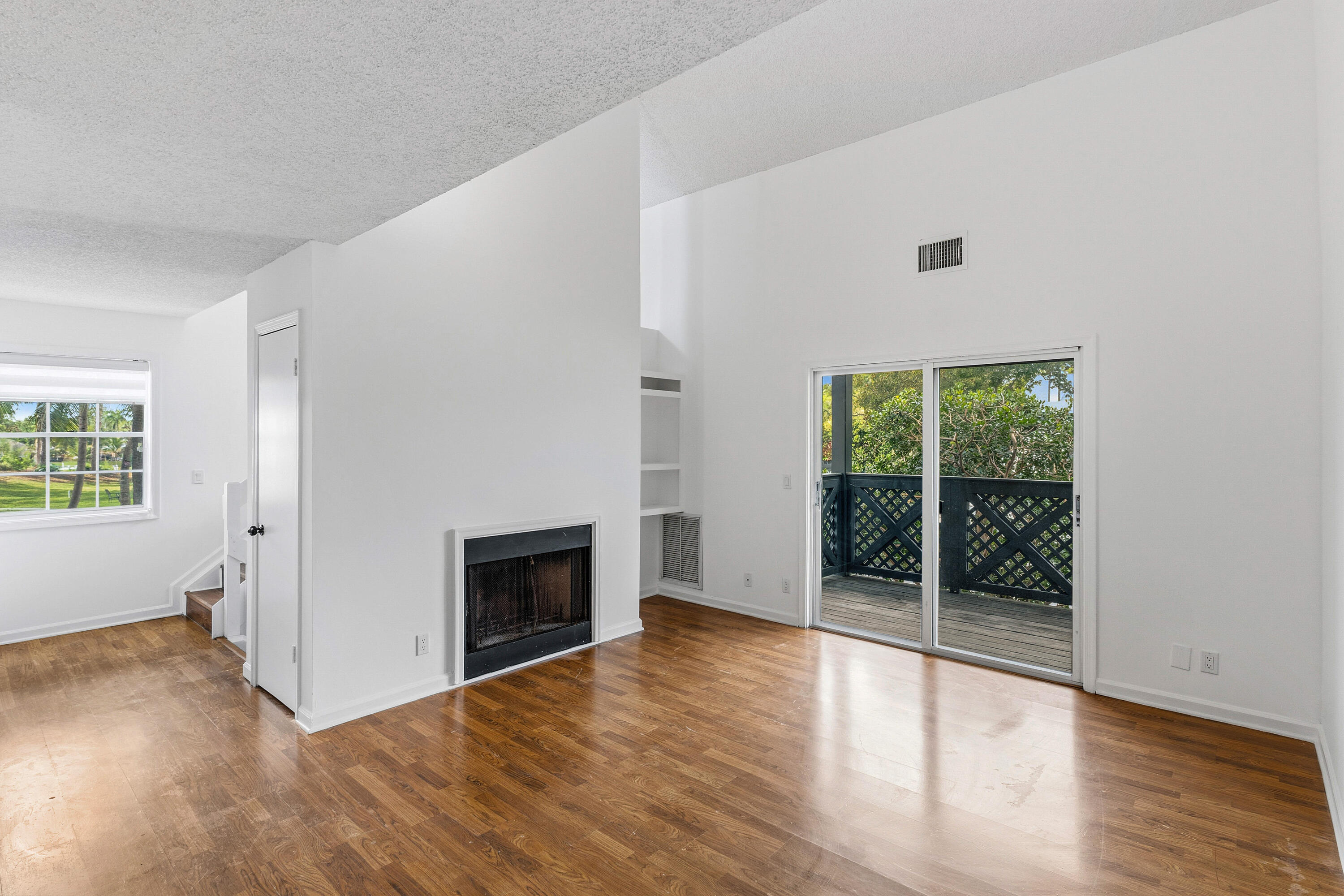 5048 Heatherhill Lane, Unit 1205 Boca Raton, FL 33486 - Photo 12 of 44 an empty room with wooden floor fireplace and windows