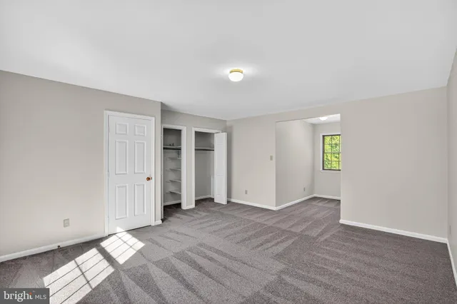 an empty room with closet and windows