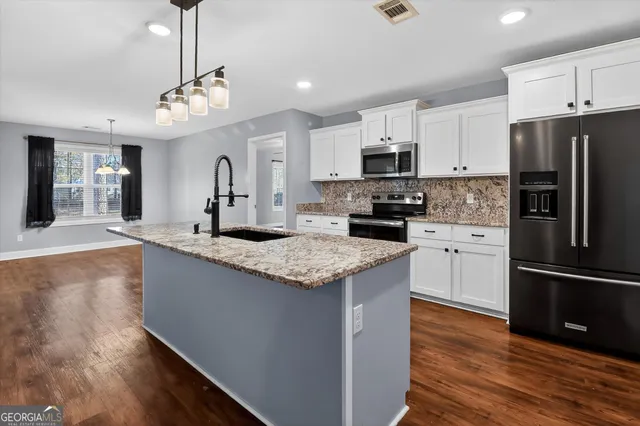 a kitchen with stainless steel appliances granite countertop a refrigerator a stove a sink dishwasher and a refrigerator with wooden floor