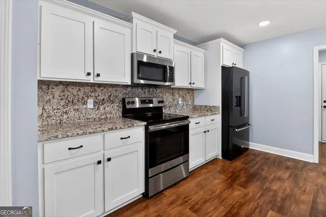 a kitchen with granite countertop white cabinets white stainless steel appliances and a sink