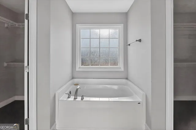 a white bath tub sitting in a bathroom next to a window
