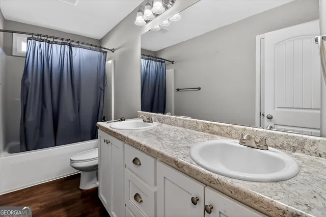 a bathroom with a granite countertop sink toilet and shower curtains