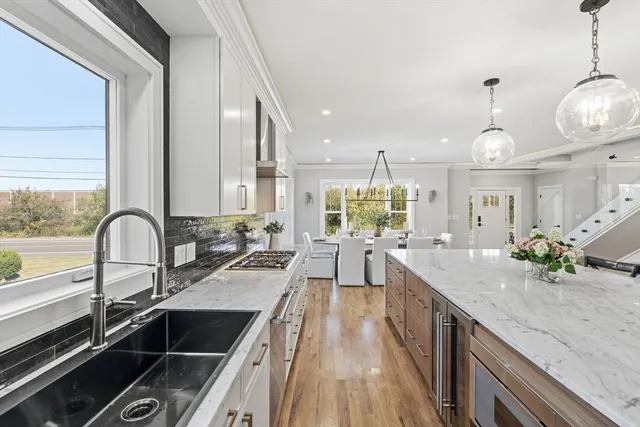 a kitchen with kitchen island granite countertop a stove a sink a large island with wooden cabinets and floor