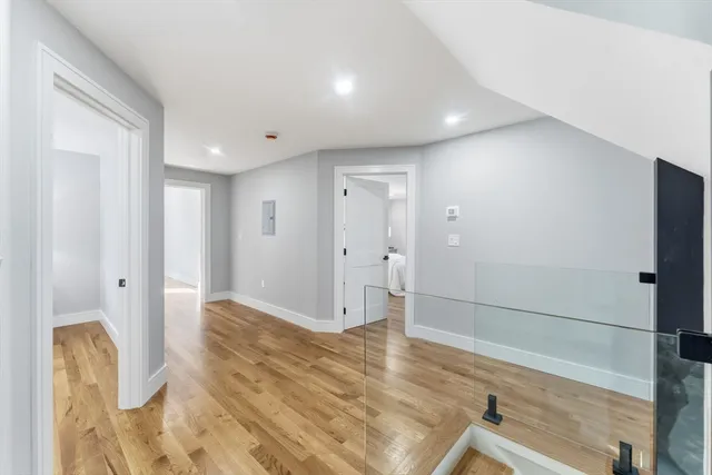 a view of a hallway with wooden floor and a bathroom