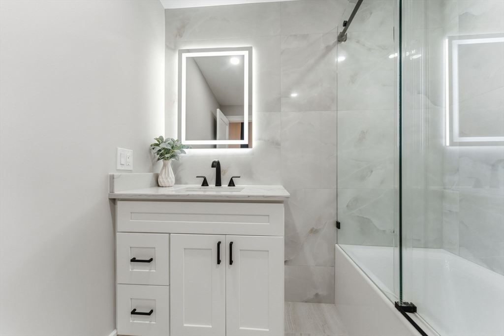 143 Hunting Road Needham, MA 02494 - Photo 34 of 42 a bathroom with a bathtub sink vanity and mirror