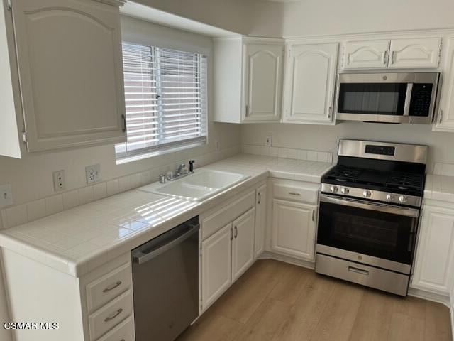 279 North Skyline Drive Thousand Oaks, CA 91362 - Photo 4 of 24 a kitchen with stainless steel appliances granite countertop a sink a stove a microwave and wooden cabinets