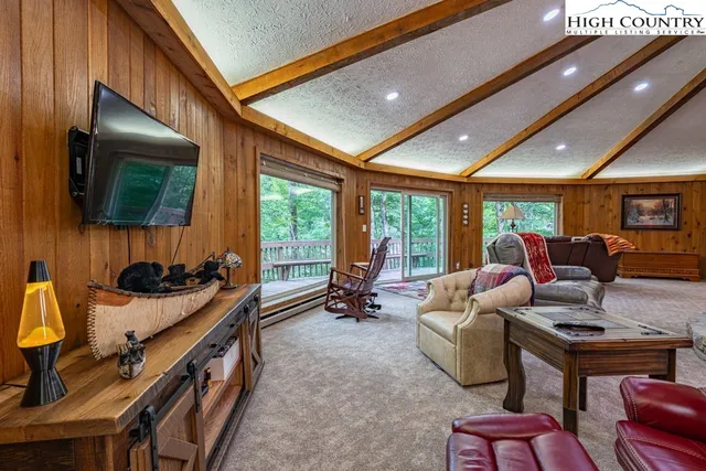 a living room with furniture a flat screen tv and floor to ceiling window