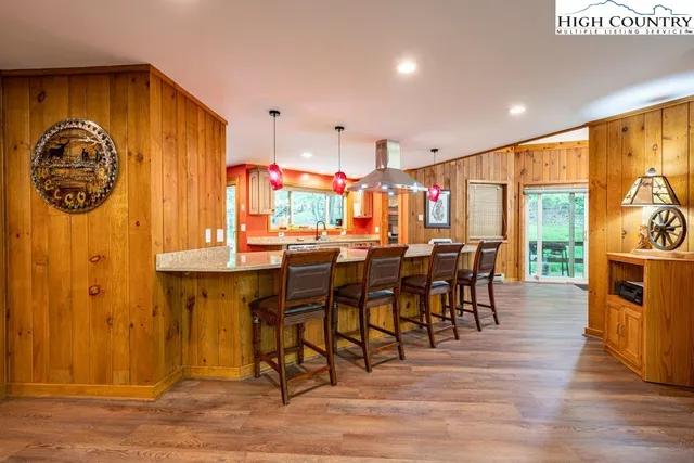 a dining hall with stainless steel appliances granite countertop a table chairs and a view of kitchen