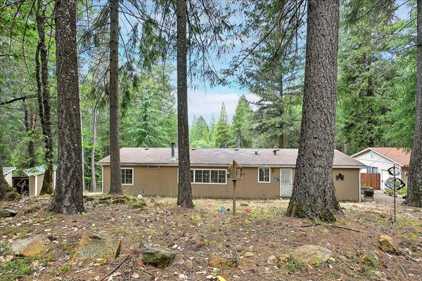 a wooden house with large trees and wooden fence