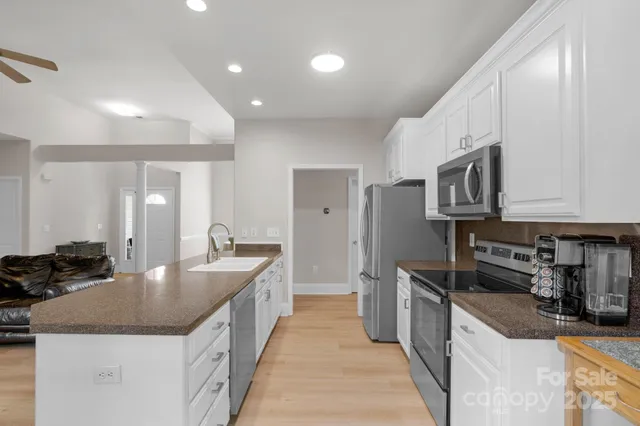 a large kitchen with stainless steel appliances granite countertop a sink a stove and a refrigerator