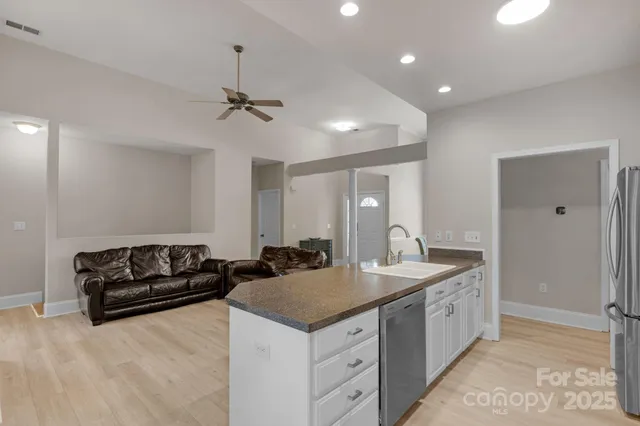 a kitchen with a stove a faucet and a view of living room