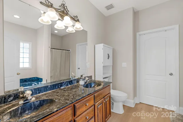 a bathroom with a granite countertop sink a toilet and a mirror